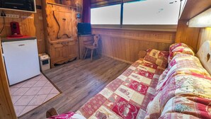Una cabaña pequeña con kitchenette, una cama individual, un escritorio pequeño y una ventana.