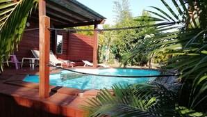 A wooden deck with a pool, lounge chairs, and a wooden cabin in the background. - Villa for 6 people, swimming pool, sea view, close to Sainte Anne beaches (SAINTE ANNE)