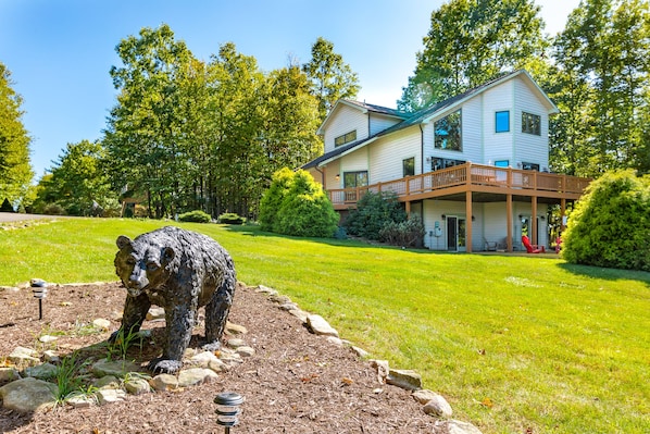 A two-story house with a balcony, surrounded by a well-maintained lawn and trees.