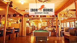 A cozy restaurant with wooden decor, a pool table, and a sign reading "IRON HORSE Restaurant & Saloon".