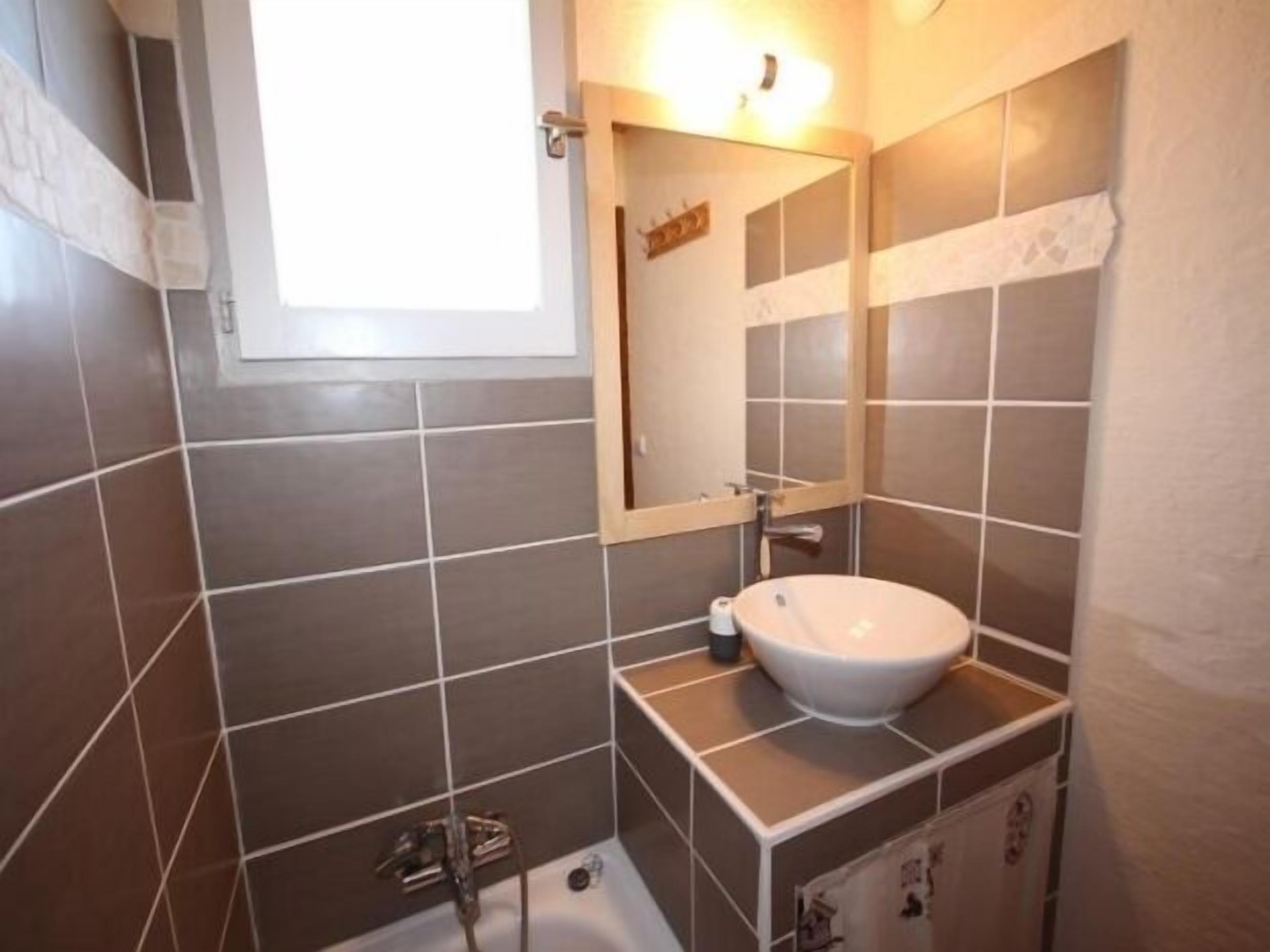 Ein Badezimmer mit einem weißen Waschbecken, einem Spiegel und einer Dusche.