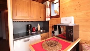 A compact kitchen with wooden cabinets, a coffee maker, a microwave, and a small sink. - Cozy apartment for 5, south balcony, near slopes (Les Saisies)