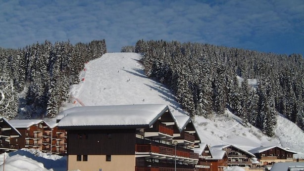 A snow-covered lodge with multiple floors and a ski slope in the background. - Cozy apartment for 5, south balcony, near slopes (Les Saisies)