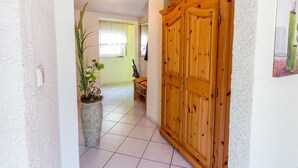 Un pasillo con un armario de madera, suelo de baldosas y una planta en maceta.