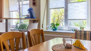 Un comedor con una mesa de madera, sillas, una cafetera y una ventana con persianas.