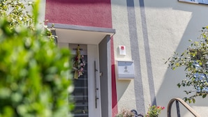 Un edificio con fachada roja y gris, una puerta blanca con manija y un buzón con el número 4.