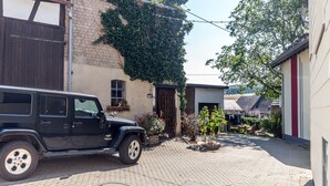 Un SUV negro estacionado en un camino de adoquines con un edificio de ladrillo y una puerta de madera al fondo.