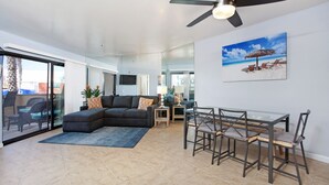 Amplia sala de estar con sofá modular, mesa de comedor de vidrio y ventilador de techo.
