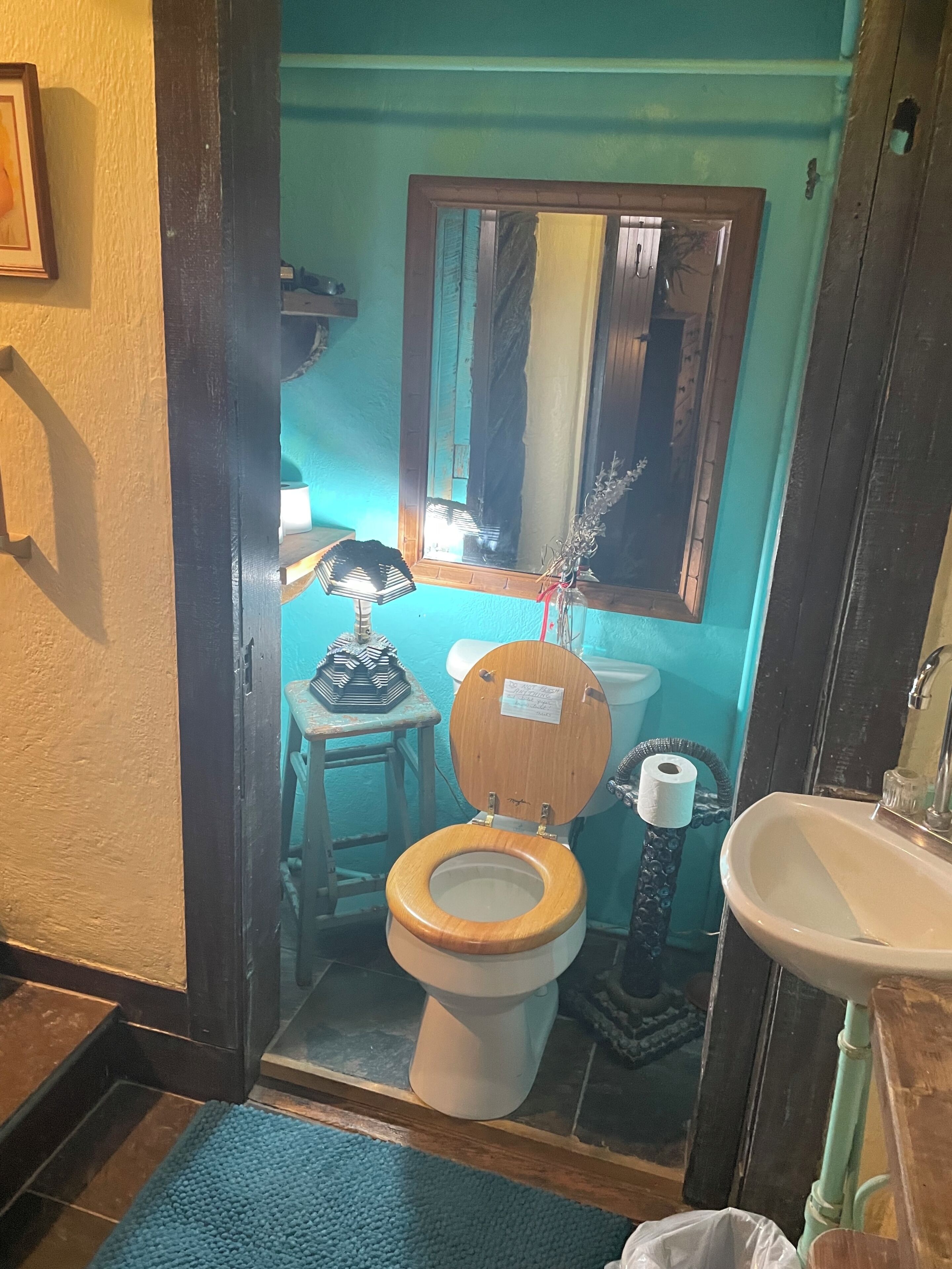A bathroom with a toilet, sink, mirror, and a blue mat.