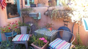 Un patio con due sedie, un tavolo e diverse piante in vaso.