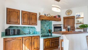 A kitchen with wooden cabinets, a tiled backsplash, and a countertop with a coffee maker.
