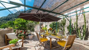 An outdoor patio with a table and chairs, surrounded by potted plants and cacti.