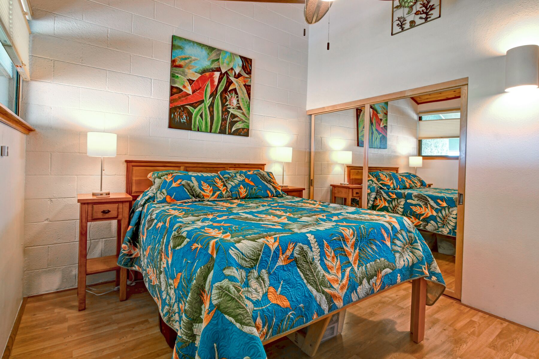 A bedroom with a large bed, two bedside tables, a mirror, and a wall painting.