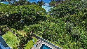 Un espace piscine avec des chaises longues et vue sur l’océan.