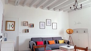 A modern living room with a grey sofa, a wooden coffee table, and a chandelier. There are framed pictures on the wall and a white cabinet. - Vacation in the heart of the Basque Country, swimming pool, quiet mountain views (Ossès)