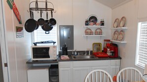 Een kleine keuken met een magnetron, spoelbak en koffiezetapparaat op het aanrecht.