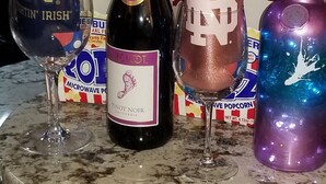 A countertop with a wine bottle, a glass, and a can of popcorn. - NOTRE DAME (South Bend)