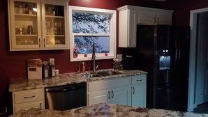 A kitchen with white cabinets, a stainless steel sink, and a black refrigerator. - NOTRE DAME (South Bend)
