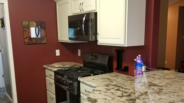 A kitchen with white cabinets, a black stove, and a granite countertop. - NOTRE DAME (South Bend)