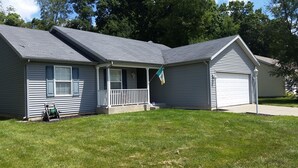 A two-story house with a front porch, a garage, and a flag. - NOTRE DAME (South Bend)
