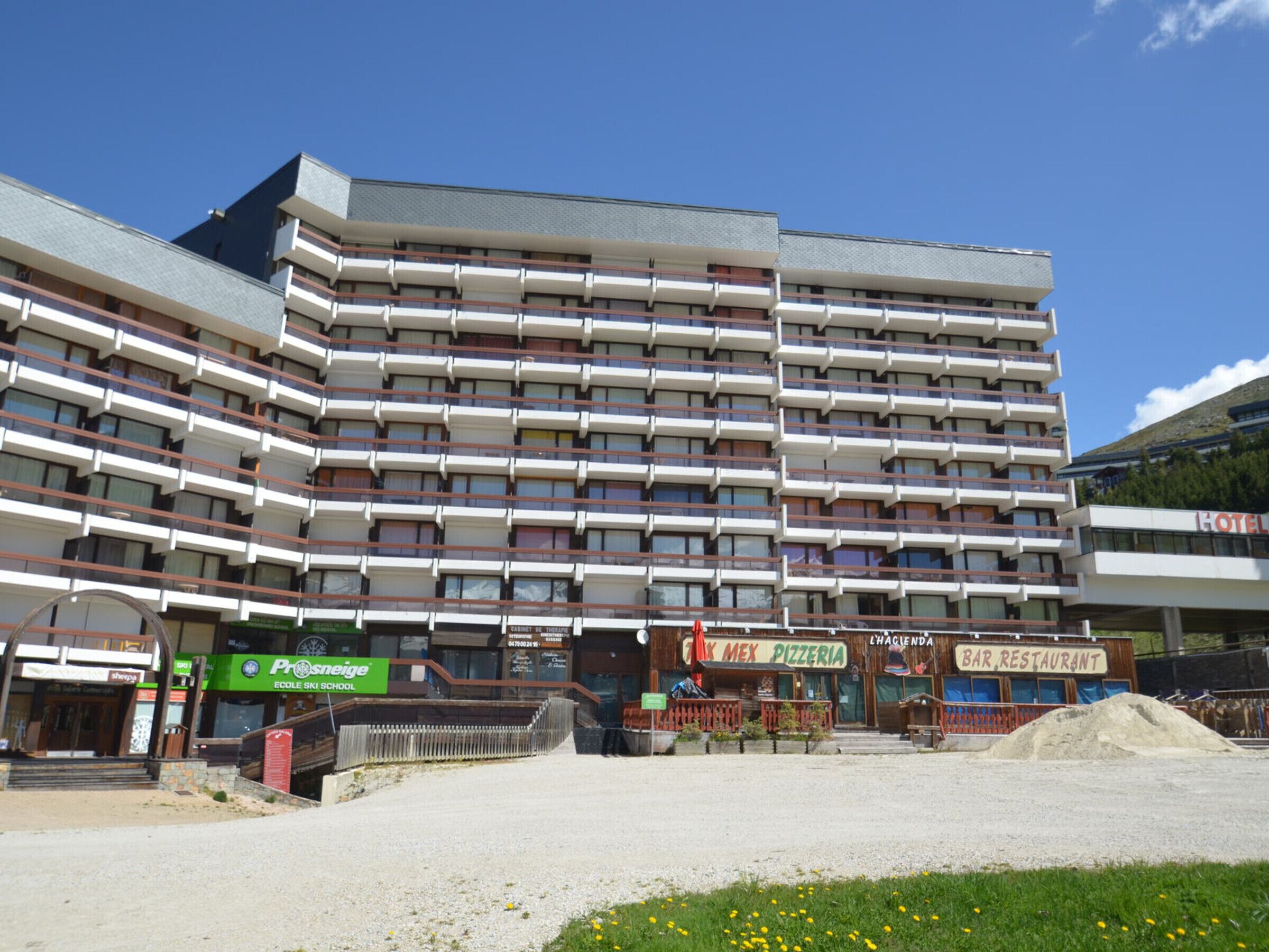 A multi-story hotel with balconies, a school, and a bar/restaurant.