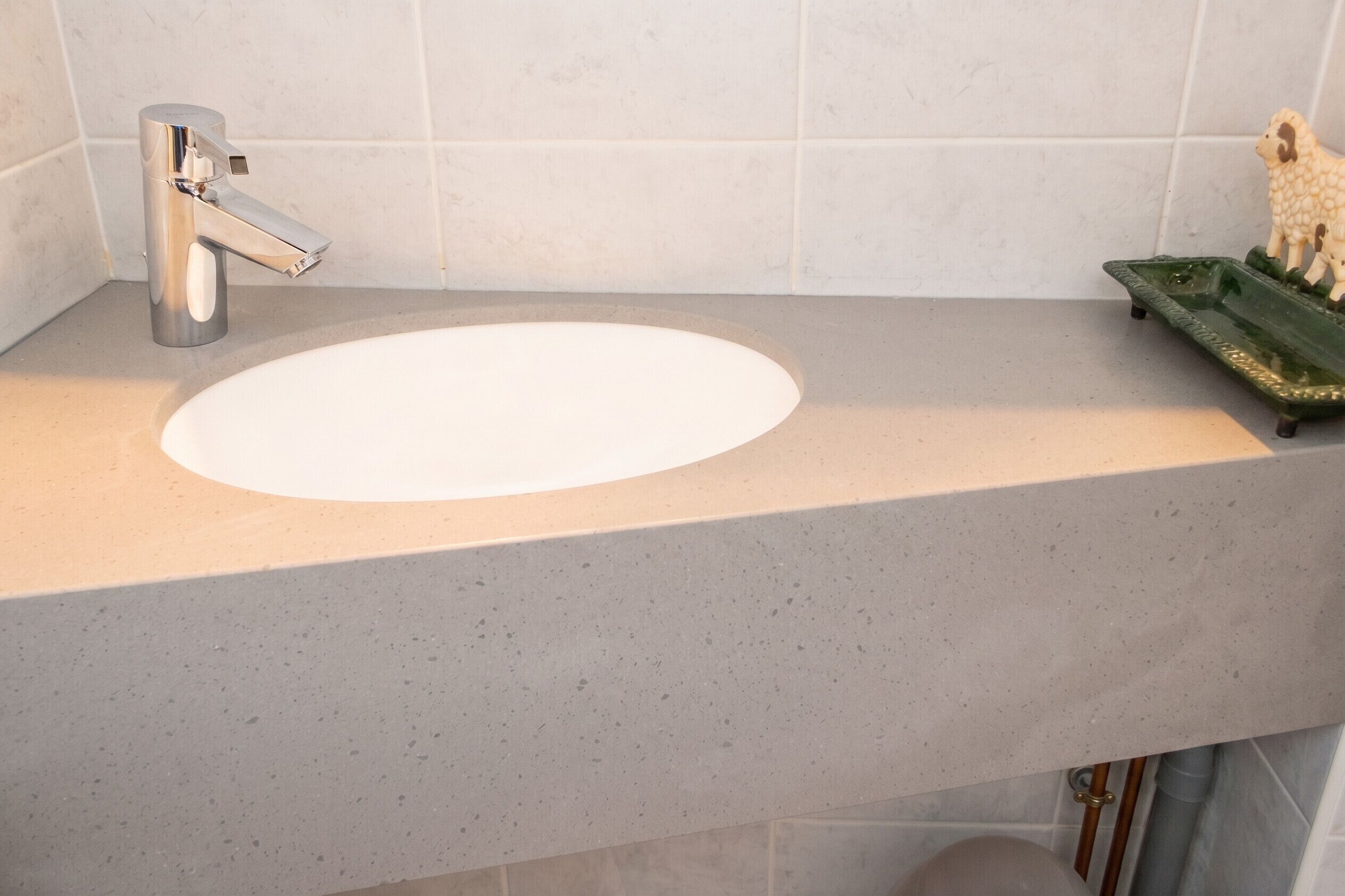 A bathroom with a white sink, a chrome faucet, and a green soap dish.