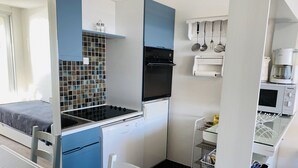 Une petite cuisine équipée d’une cuisinière, d’un four à micro-ondes et d’un petit réfrigérateur.