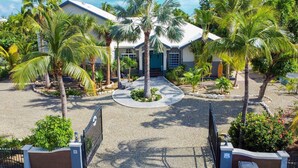 A gated entrance with a palm tree and a building with a blue door. - Spacious Villa for Families & Groups • Pool + Waterslide. Rent 4 or 5 Bedrooms (Providenciales)