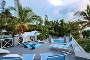 Relax by the pool surrounded by lush greenery and palm trees.