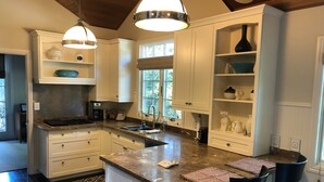 A modern kitchen with white cabinetry, a central island, and pendant lighting. - Creekside Casita walking distance to downtown San Carlos (San Carlos)