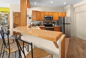 A kitchen with wooden cabinets, a stainless steel refrigerator, a microwave, and a built-in oven.