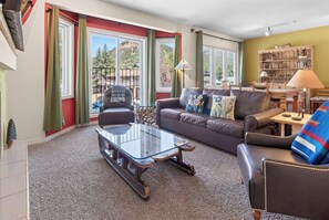 A living room with a leather sofa, a glass coffee table, and a bookshelf.