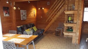 Ein gemütliches Holzhaus-Interieur mit Essbereich, Sofa und Treppe.