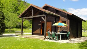 Eine Holzhütte mit Veranda, Tisch und Stühlen sowie einem bunten Sonnenschirm.