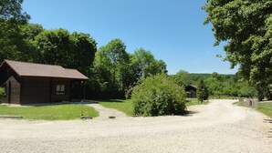 Eine rustikale Holzhütte mit Kiesweg, umgeben von üppiger Vegetation und Bäumen.