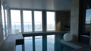 Une piscine intérieure moderne, dotée de grandes baies vitrées offrant une vue sur la mer.