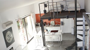 A modern apartment with a grey sofa, a dining area, a kitchen, and a staircase. - A PEACEFUL HEAVEN IN THE HEART OF LUBERON (Cucuron)
