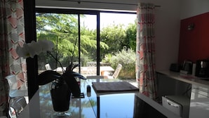 A modern kitchen with a glass-top island, a potted plant, and a view of the outdoors. - A PEACEFUL HEAVEN IN THE HEART OF LUBERON (Cucuron)