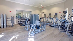 A gym with cardio machines, weight machines, and dumbbells.