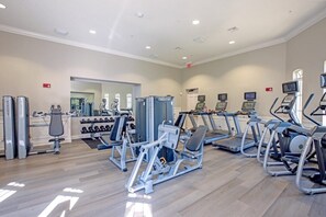 Een fitnessruimte met cardioapparatuur, krachttoestellen en gewichten.