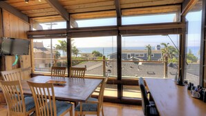 Comedor con mobiliario de madera y amplios ventanales con vistas al mar.