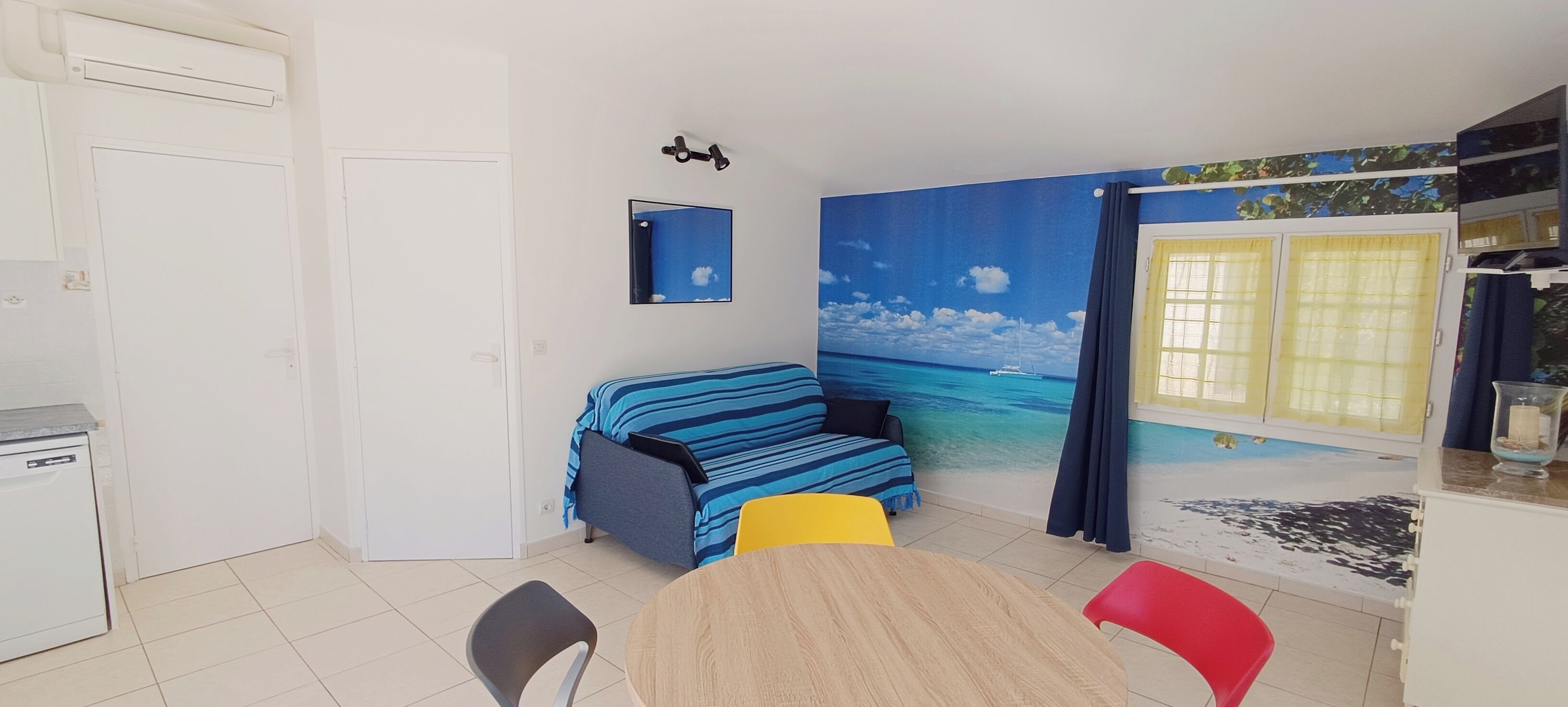 A compact room with a bed, a dining table, and a small kitchen area.