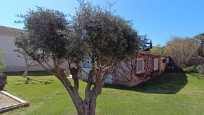 A residential property with a well-maintained lawn, a tree, and a house with a tiled roof. - GITE FOR 4 PERS WITH POOL (Agde)