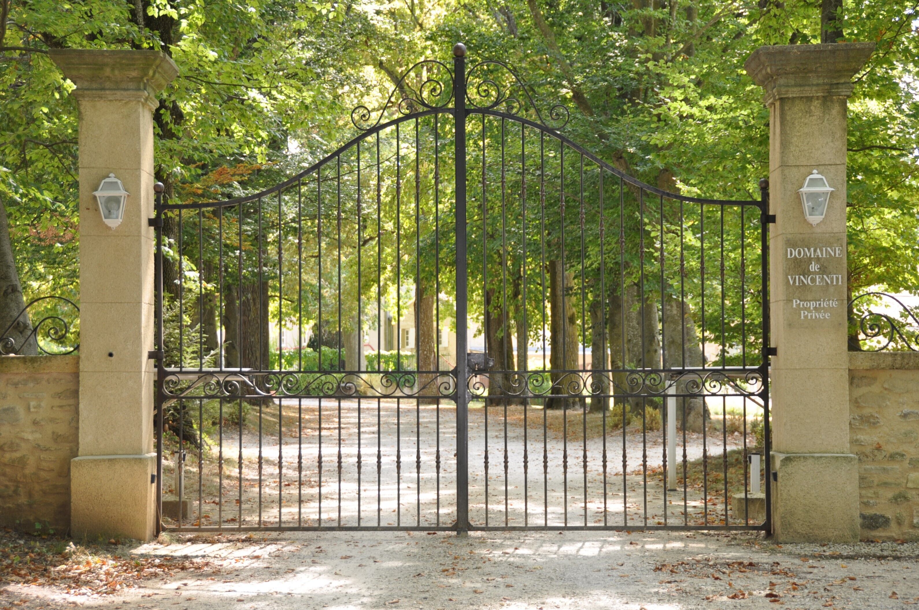 Una porta de ferro forjat amb un piló de pedra a cada costat, un senyal que diu "Domaine de Vincenti Proprieté Privée", i un camí que s'endinsa per una zona boscosa.