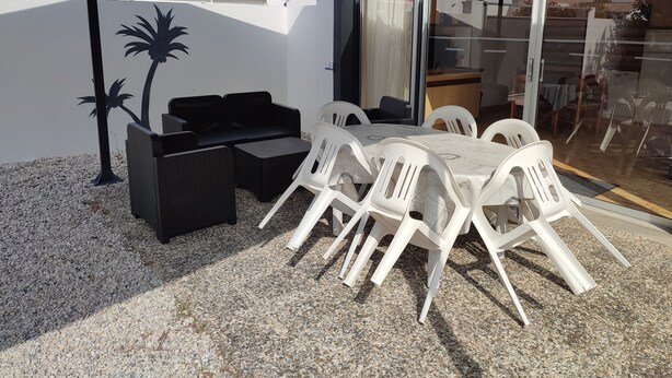 An outdoor patio with a table and chairs, a sofa, and a decorative palm tree. - LARGE PRIVATE COURT HOUSE CLOSED (Saint Palais sur Mer)
