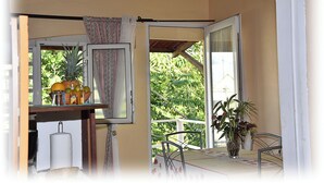 A balcony with a table, chairs, a potted plant, and a window with curtains. - T2 Apartment Countryside View (st joseph)