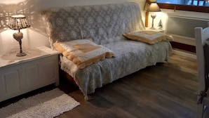 Una sala de estar acogedora con un sofá, un reloj en la pared y una ventana con cortinas.