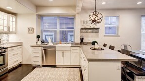 A modern kitchen with white cabinetry, a central island, and a dining area with a long table.