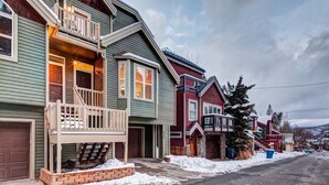 A row of two-story houses with front porches and a snow-covered street.