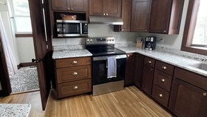 A kitchen with wooden cabinets, a stainless steel oven, a microwave, and a coffee maker.
